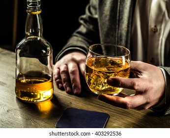 Man wearing jacket holding a glass of whiskey at the bar counter