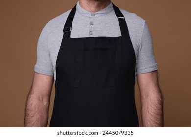 Man wearing kitchen apron on brown background, closeup. Mockup for design - Powered by Shutterstock