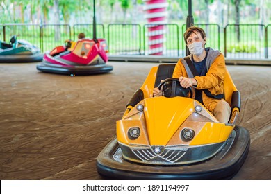 Man wearing a medical mask during COVID-19 coronavirus having a ride in the bumper car at the amusement park