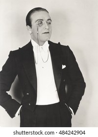 Man Wearing Monocle And Tuxedo With Hands In Pockets