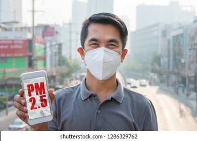 Man Wearing The N95 Respiratory Protection Mask And Holding Smart Phone App With PM 2.5 Screen