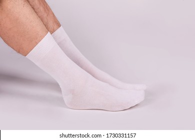 Man Wearing New White Cotton Blank Socks On A White Background. Detailed Closeup Studio Shot. Male Legs Wearing Socks
