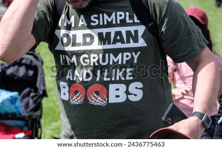 A man wearing an offensive T-shirt with the caption 'I'm a simple old man I'm grumpy and I like boobs'. 