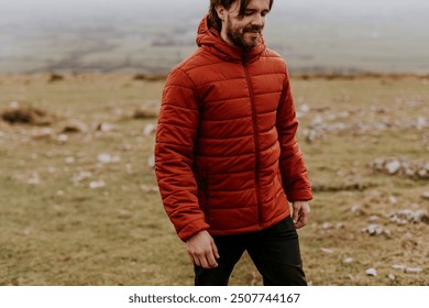 Man wearing orange puffer jacket, walking on hill - Powered by Shutterstock