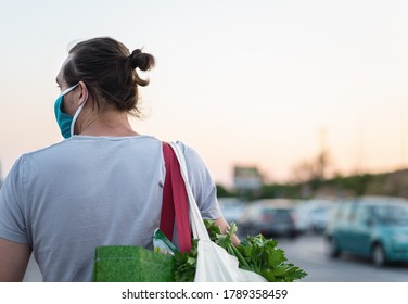 Man Wearing Protective Medical Mask And Carrying White Reusable Canvas Bag For Food Shopping With Vegetables Inside