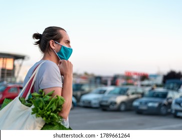 Man Wearing Protective Medical Mask And Carrying White Reusable Canvas Bag For Food Shopping With Vegetables Inside