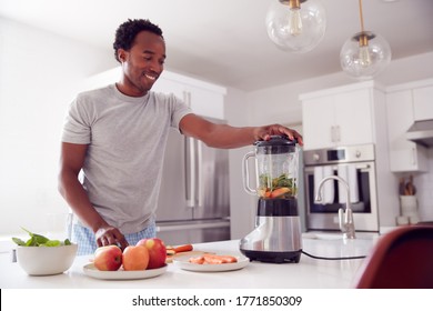 Man Wearing Pyjamas Standing In Kitchen Putting Fresh  Fruit And Vegetables Into Blender - Powered by Shutterstock