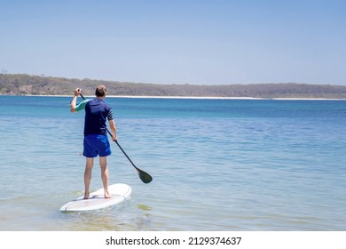 Man Wearing Rash Guard On A Stand-up Paddle Board At The Ocean Bay In Australia. SUP Water Sport Activity SUP Water Sport Summer Activity