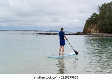 Man Wearing Rash Guard On A Stand-up Paddle Board At The Ocean Bay In Australia. SUP Water Sport Activity SUP Water Sport Summer Activity