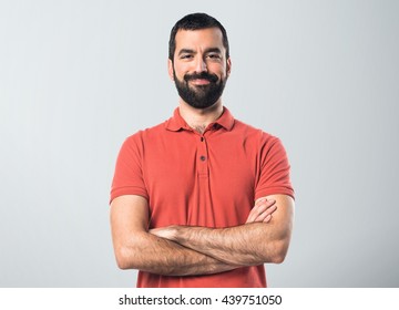 Man Wearing Red Polo Shirt With His Arms Crossed Over Grey Background