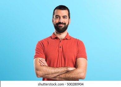 Man Wearing Red Polo Shirt With His Arms Crossed Over Colorful Backgound