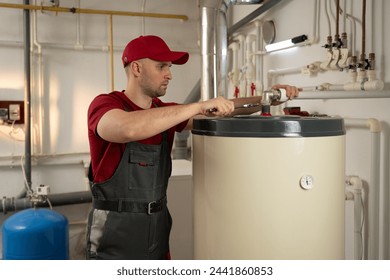 A man wearing a red shirt is shown fixing a water heater. He carefully inspects the heater, troubleshoots the issue, and repairs it efficiently.