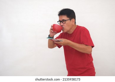 Man Wearing A Red T-shirt Sipping Noodle Soup From A Red Bowl.