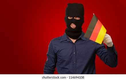 Man Wearing Robber Mask And Holding Flag On Red Background