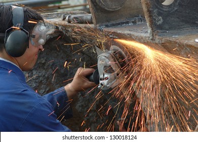 man wearing safety goggles grinds welding splatter off a machine - Powered by Shutterstock