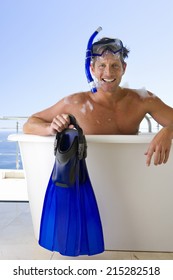 Man Wearing Snorkle And Holding Flippers Whilst In Bubble Bath, Smiling, Portrait