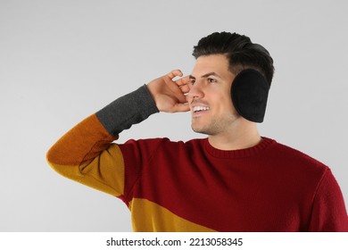 Man Wearing Stylish Earmuffs On Light Background