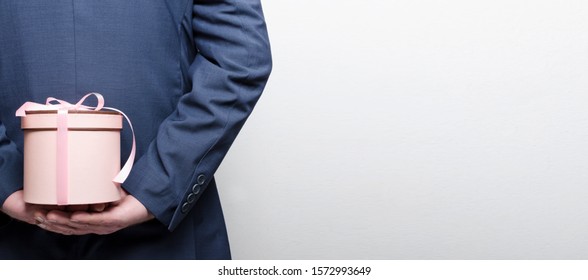 Man Wearing Suit And Hiding The Romantic Gift Box Behind His Back.Empty Space For Text