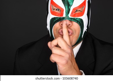 Man Wearing A Suit And Luchador Mask Making A Gesture To Be Silent.