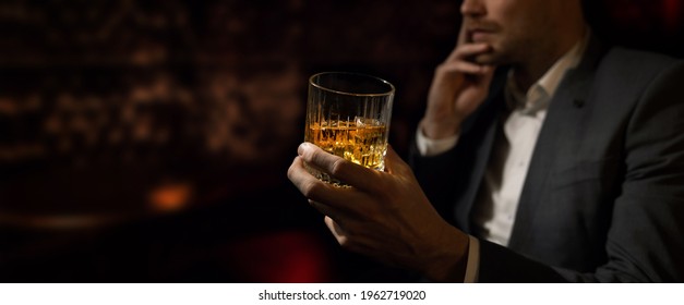 Man Wearing Suit Sits In The Luxury Bar In Gentlemen Club And Drink Whiskey. Copy Space