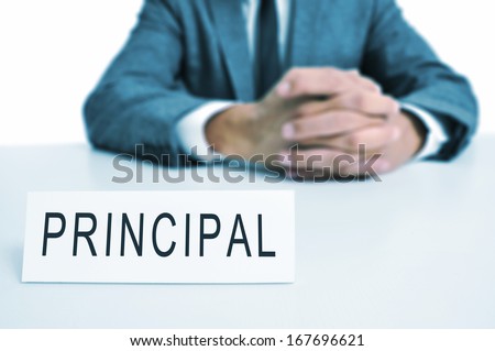 a man wearing a suit sitting in a desk with a signboard in front of him with the word principal written in it