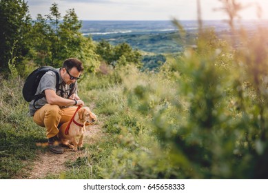 Man Wearing Sunglasses With A Small Yellow Dog Resting At The Hiking Trail