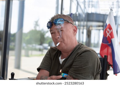 A man wearing sunglasses while smoking outdoors, perfectly embodying a laidback, casual atmosphere of relaxation - Powered by Shutterstock