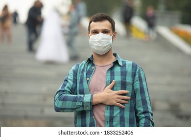 Man Wearing Surgical Mask Greets With His Hand Over The Heart. The New Greeting Recommended By The World Health Organisation Due To The Coronavirus Covid-19 Pandemic.