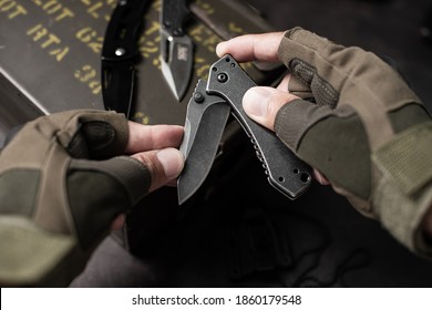 The man wearing tactical gloves using folding knife.