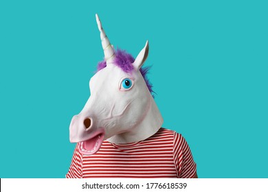 man wearing a unicorn mask and a red and white striped t-shirt on a blue background with some blank space around him