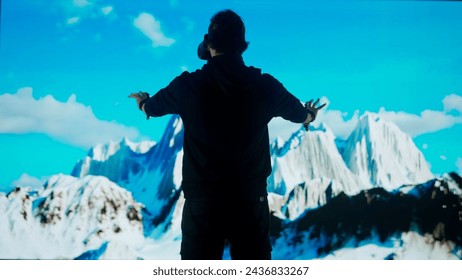 Man wearing virtual reality glasses stands in front of big digital screen playing moving mountains, cyber visual background, back shot. - Powered by Shutterstock