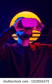 Man Wearing Virtual Reality Goggles. VR Head Set Videogame In 80's Synthwave And Retrowave Futuristic Aesthetics.