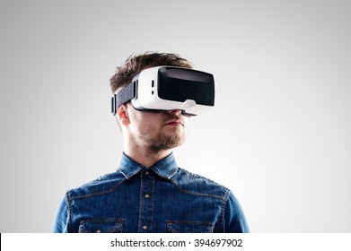 Man wearing virtual reality goggles. Studio shot, gray backgroun