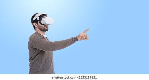 Man wearing a virtual reality headset, interacting with something unseen, against a plain blue background. Concept of immersive technology