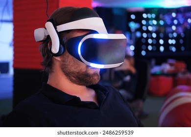 Man wearing VR Glasses. Surprised adult male having fun play VR headset virtual reality goggle, 3D cyber space. Neon blue red UV lighting. Digital technology, game - Powered by Shutterstock