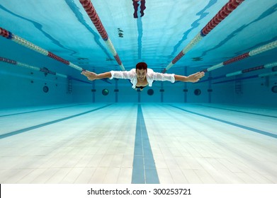 Man Wearing White Shirt Inside Swimming Pool. Underwater Image.