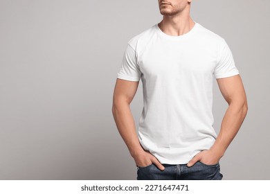 Man wearing white t-shirt on light grey background, closeup. Mockup for design