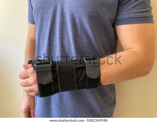 A man wearing wrist\
splint. Hand injury.  Sprained arm with splint. Pain in the wrist.\
Black wrist splint for left hand. Broken wrist and arm recovery\
with immobilizer.