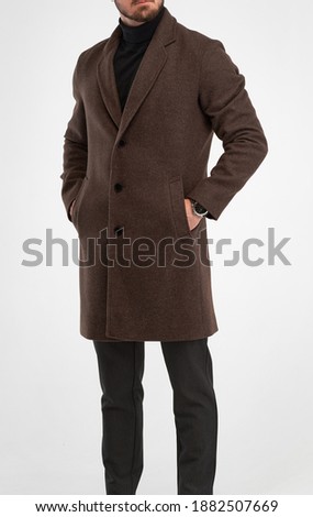 man wears brown overcoat. isolated studio shot of stylish man in dark full length dark brown greatcoat