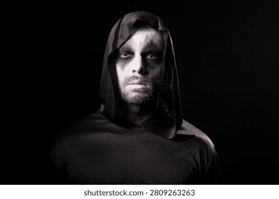 Man wears dramatic demon makeup for a Halloween party portrait isolated on a black background, creating a dark costume character, with festive nightlife, costume interaction and Halloween atmosphere.