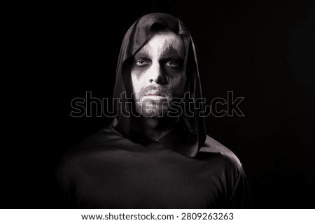 Man wears dramatic demon makeup for a Halloween party portrait isolated on a black background, creating a dark costume character, with festive nightlife, costume interaction and Halloween atmosphere.