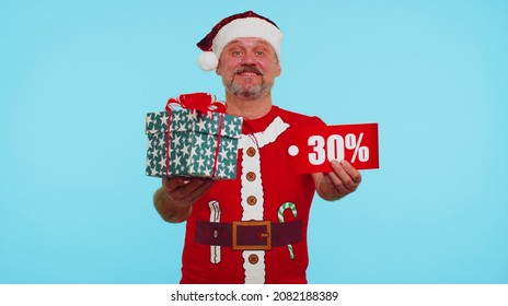 Man wears red New Year t-shirt showing gift boxes and 30 Percent discount inscriptions banner text. Black Friday. Advertising low prices shopping. Blue studio wall background. Merry Christmas holidays - Powered by Shutterstock