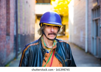 A man wears some interesting clothes including multiple layers and a hat with a helmet.