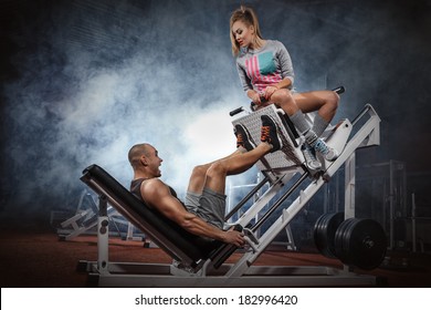 Man weightlifter doing leg presses with his trainer up on simulator  - Powered by Shutterstock