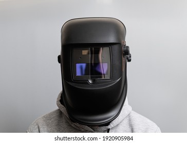 Man in a welding black mask on a light gray background, close-up