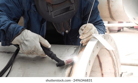 A man is welding a pipe. Concept of hard work and dedication, as the man is focused on his task and using a blowtorch to heat the pipe - Powered by Shutterstock