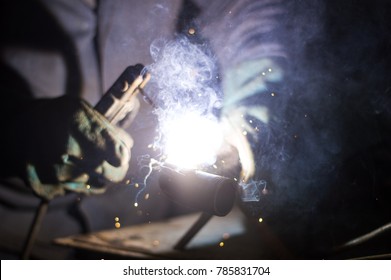 A man welds a metal with a welding machine
