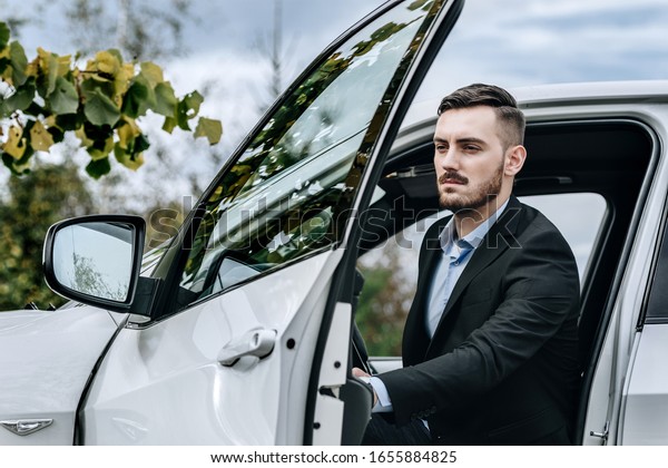 Man
in a well tailored suit jacket next to a luxury
car
