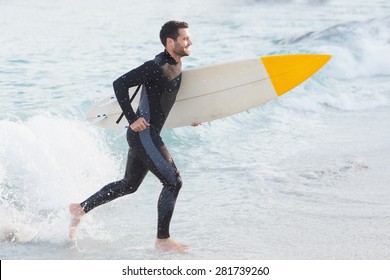 Man in wetsuit with a surfboard on a sunny day at the beach - Powered by Shutterstock