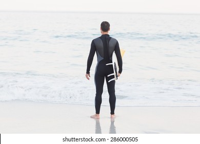 Man in wetsuit with a surfboard on a sunny day at the beach - Powered by Shutterstock